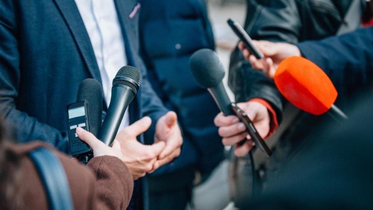 Microfoni e registratori tesi verso una persona in giacca durante un'intervista